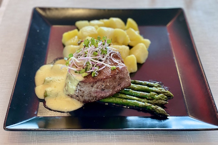 Beef sirloin steak on roasted asparagus with hollandaise sauce and boiled potatoes